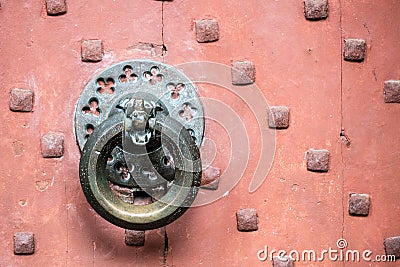 Detail of antique bronze door knocker on old red door Stock Photo