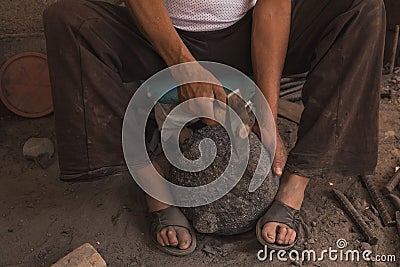 Detail of the craftsman`s hands carving the stone to make molcajetes, traditional Mexican crafts Stock Photo