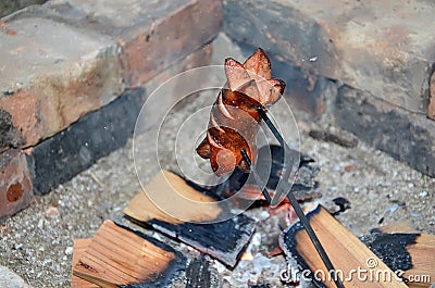 Detail of grilling sausage over a fire in summer Stock Photo