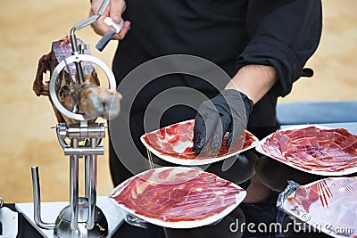 Detail of the hand of a professional Iberian ham cutter placing the slices on a plate. Concept pork, food, ham, iberian, spain, Stock Photo