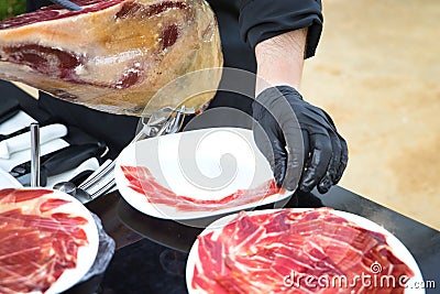 Detail of the hand of a professional Iberian ham cutter placing the slices on a plate. Concept pork, food, ham, iberian, spain, Stock Photo