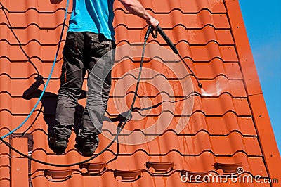 Worker cleaning metal roof with high pressure water Stock Photo