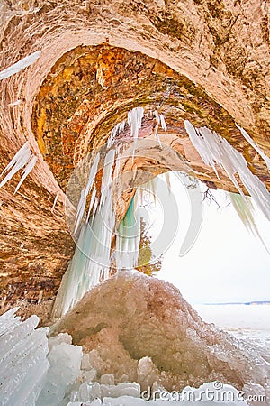 Detail of ice cave entrance with wavy rock formations and frozen icicles Stock Photo