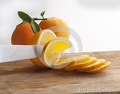 Detail of a knife cutting a slice of orange on a wooden board Stock Photo