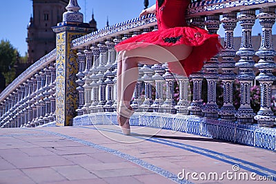 Detail of legs and feet of adult female Hispanic classical ballet dancer in red tutu doing figures leaning on a nice tiled Stock Photo