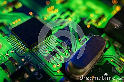 Detail of a microprocessor, resistors and capacitors soldered to a green glowing PCB Stock Photo