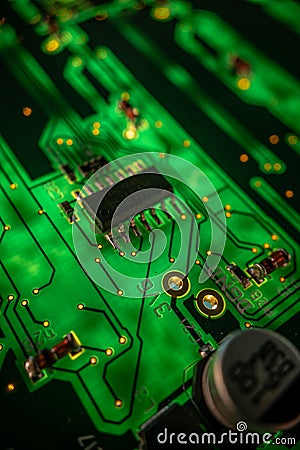 Detail of a microprocessor, resistors and capacitors soldered to a green glowing PCB Stock Photo