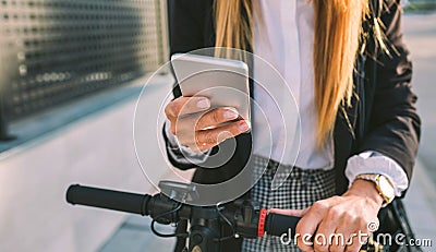 Detail of mobile of businesswoman with electric scooter Stock Photo