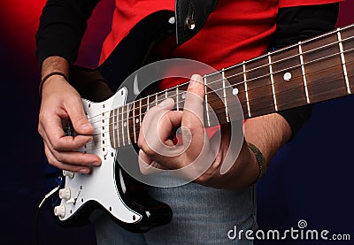 Detail of a musician playing a black electric guit Stock Photo