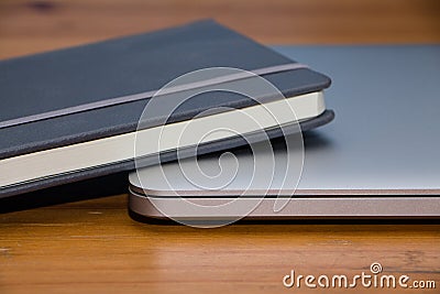 Detail of a notebook and laptop on wooden table Stock Photo