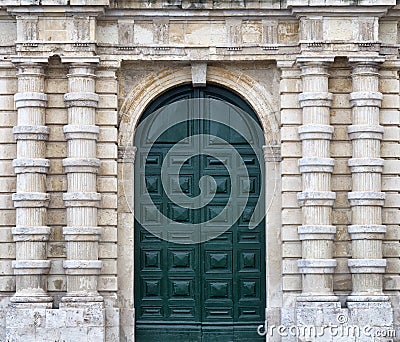 Detail of an old urban building stone facade with tall green wood door and decorative columns Stock Photo