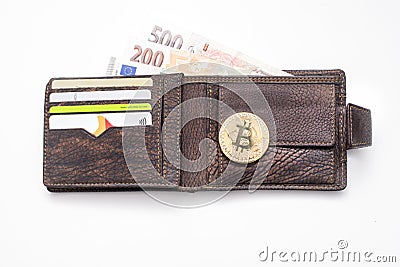 Detail of an open leather wallet with a big golden Bitcoin, fiat notes and credit cards and blue lit keyboard in Editorial Stock Photo