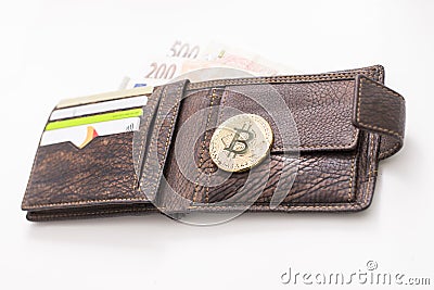 Detail of an open leather wallet with a big golden Bitcoin, fiat notes and credit cards and blue lit keyboard in Editorial Stock Photo