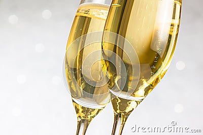 Detail of a pair of flutes of golden champagne on silver bokeh Stock Photo