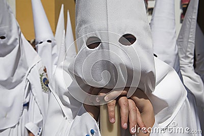 Detail penitent white holding a candle during palm sunday Holy Week in Arco del Postigo, Sevilla Editorial Stock Photo