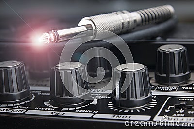 Detail of the plug of an electric guitar cable resting on the panel of an amplifier Stock Photo