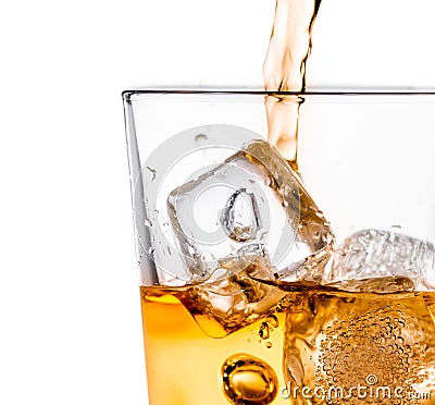 Detail of pouring scotch whiskey in glass with ice cubes on white Stock Photo