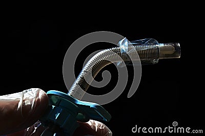 Detail of reinforced tracheostomy cannula used in emergency and icu held in doctor left hand on dark background Stock Photo