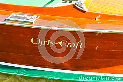 Detail of side of a classic wood Chris-Craft boat with logo painted on wood and water lapping bottom visible at bottom Editorial Stock Photo