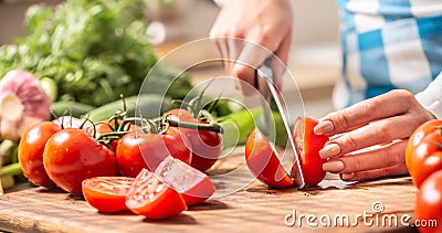 Detail of a tomato freshly cut into halves on a cutting board with cucumber, garlic and more tomatoes aside Stock Photo