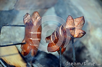 Detail of two grilling sausage over a fire in summer Stock Photo