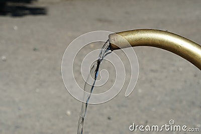 Detail view to current of clean drinking water flows from cock-metal or yellow brass, copper faucet Stock Photo