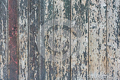 Detail of a wooden wall of a barn made of vertical, weathered boards with peeling green and red paint Stock Photo
