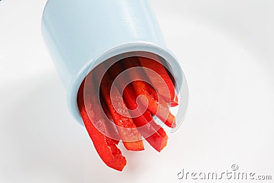 Detailed isolated copy space close up food shot of a pile of slices of fresh wet sweet red bell pepper in a blue round clay Stock Photo