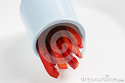 Detailed isolated copy space close up food shot of a pile of slices of fresh wet sweet red bell pepper in a blue round clay Stock Photo