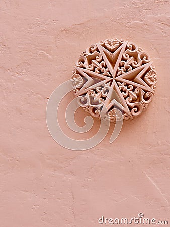 Detailed stucco heraldic emblem of Malta on rough painted wall of pastel colour. Vertical photo Stock Photo