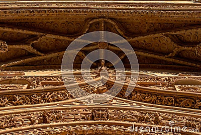 Detailed view from below of the ornaments on the cornice of the main door with bas-reliefs of fantastic animals, saints, chimeras Stock Photo