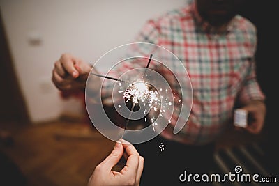 Details with the hands of a couple holding sparklers hand fireworks Stock Photo