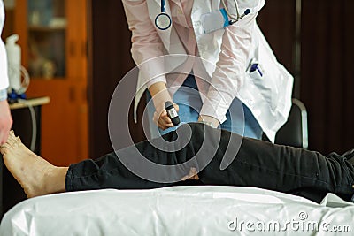 Details with the hands of a young female medic testing the knee reflexes of a patient Stock Photo