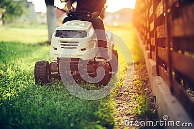 Details of landscaping and gardening. Worker riding industrial lawnmower Stock Photo