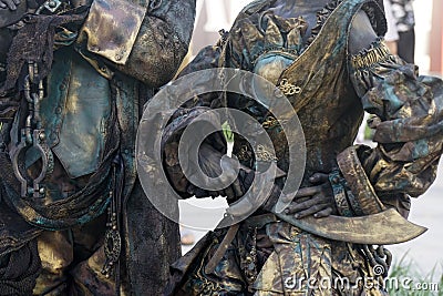 Details of Living statue of two pirates. Woman and man dressed in bronze costumes with hats and weapons pose as a realistic human Stock Photo