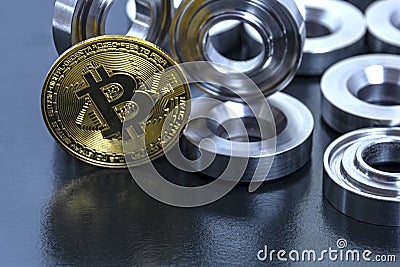 Details machined on a lathe and bitcoin on a black background. The concept of real and virtual income, earnings on the Internet Stock Photo