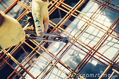 details with worker using wire rod and pliers for securing reinforcement steel bars on house building Stock Photo