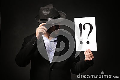 Detective holding sheet of paper with exclamation and interrogation marks on dark background Stock Photo