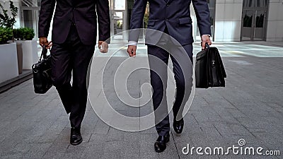 Determinate businessmen walking out office center holding briefcases cooperation Stock Photo