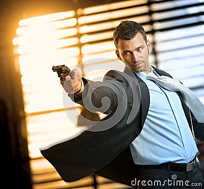 Determined action hero wearing suit holding gun Stock Photo