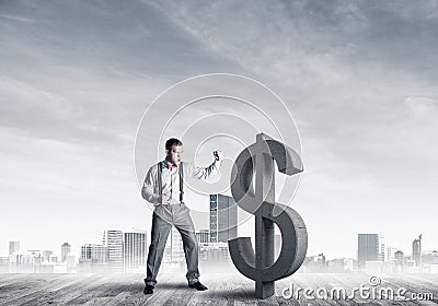 Determined banker man against modern cityscape breaking dollar concrete figure Stock Photo