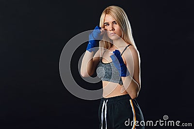 Determined blonde female boxer in blue handwraps gets prepared for fight Stock Photo