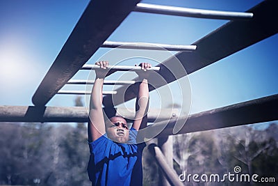 Determined boy exercising on monkey bar during obstacle course Stock Photo