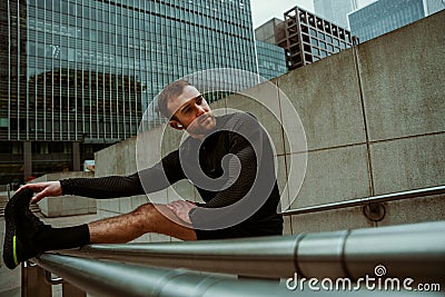 Determined caucasian male athlete stretching calves while fitness training in city streets Stock Photo