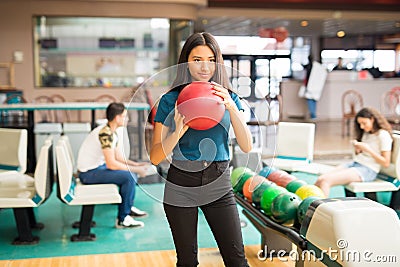 Determined Girl Getting Ready To Throw Bowling Ball At Alley Stock Photo