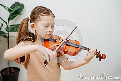 Determined little girl learning to play violin, focusing on her fingers pressing Stock Photo