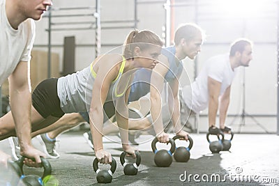 Determined people doing pushups with kettlebells at crossfit gym Stock Photo