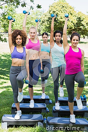 Determined women doing step aerobics in park Stock Photo