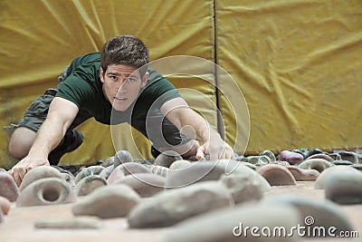 Determined young man climbing up a climbing wall in an indoor climbing gym, directly above Stock Photo