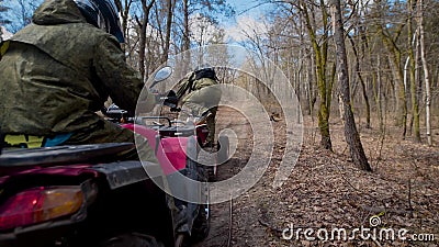 Deux athlètes qui portent des casques de protection et des vêtements sautent sur l'ATV et montent vite le long de la forêt d'auto banque de vidéos Deux athlètes qui portent des casques de protection et des vêtements sautent sur l'ATV et montent vite le long de la forêt d'auto banque de vidéos